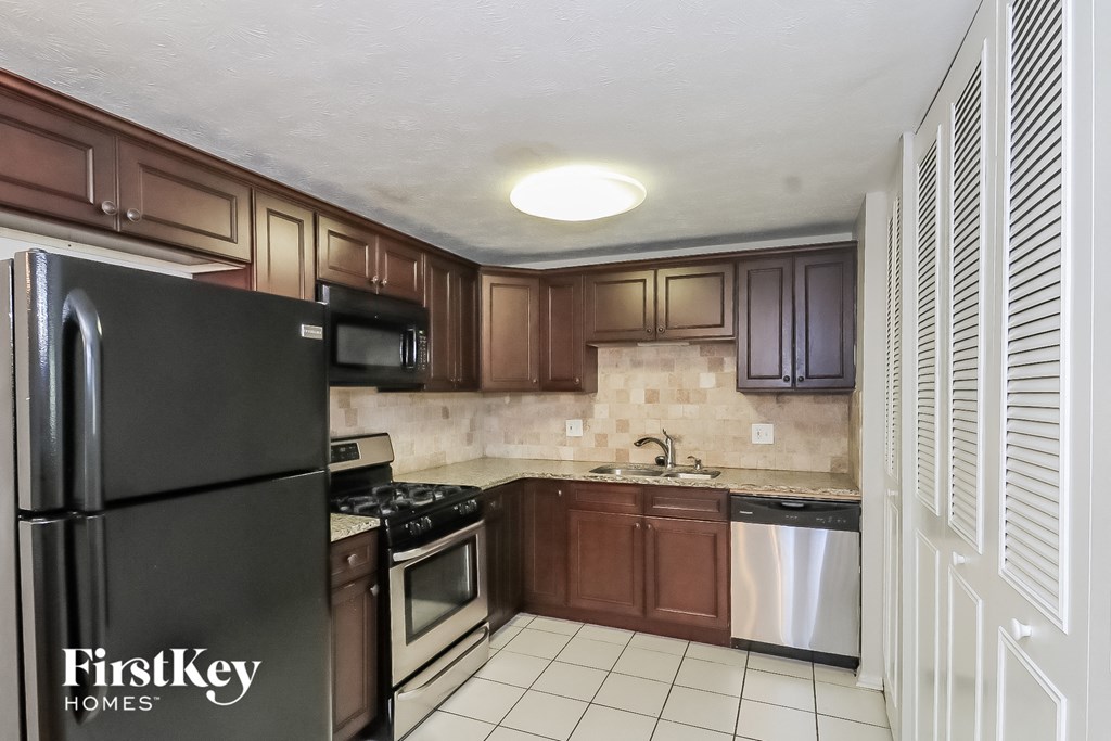 A kitchen with a black fridge and brown cabinets.