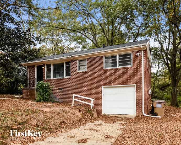 A brick house with a white garage door and a white fence in front.