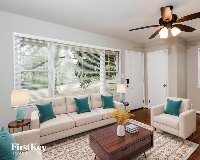 A living room with a white couch, a coffee table, and a ceiling fan.