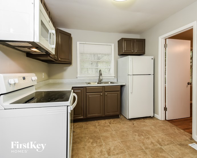 A kitchen with a white oven and a white fridge.