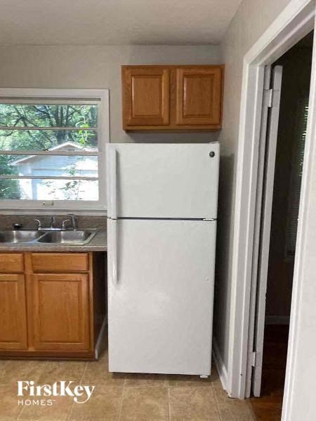A white refrigerator in a kitchen with wooden cabinets.