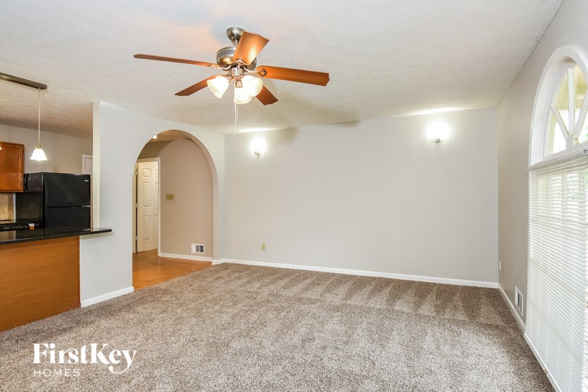 an empty living room with a ceiling fan and a carpet