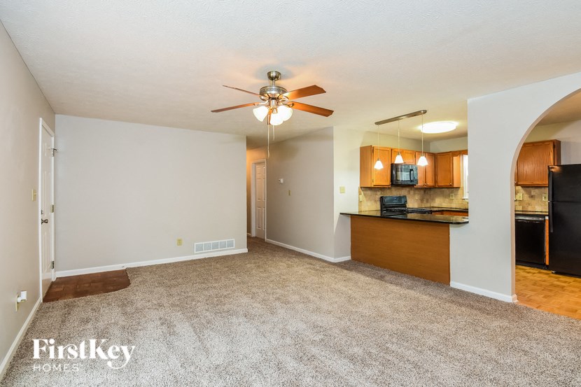 an empty living room and kitchen with a ceiling fan