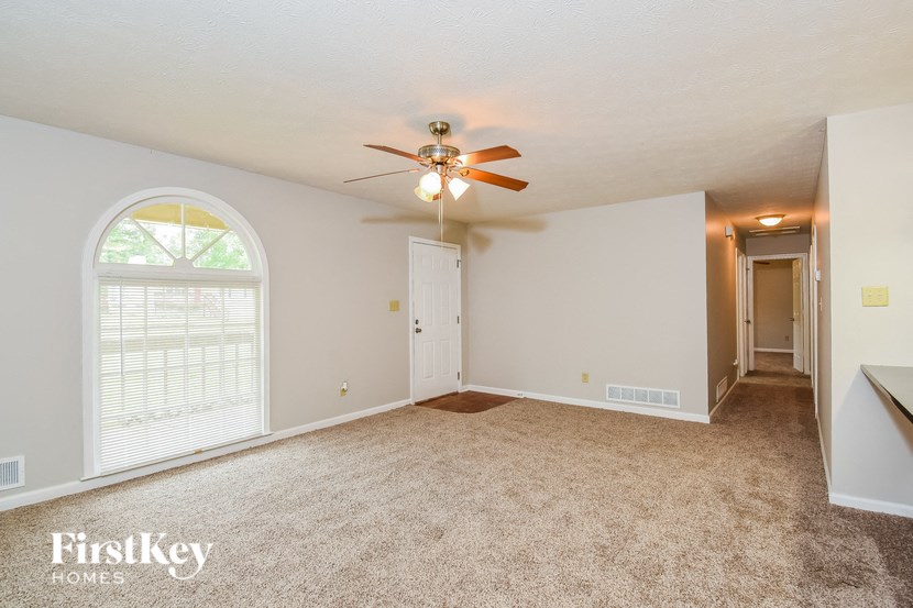 an empty living room with a ceiling fan and a large window