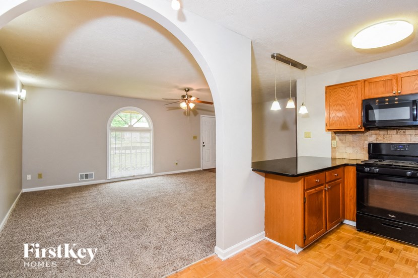 an empty kitchen and living room with an arched door
