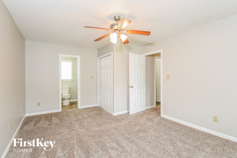 a empty living room with a ceiling fan and a door to the bathroom