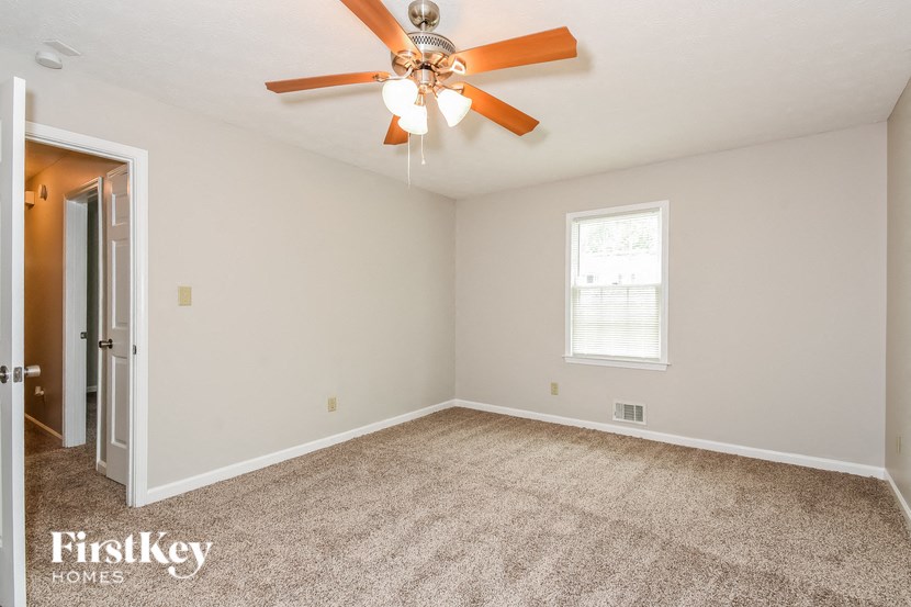 an empty bedroom with a ceiling fan and a door to a closet