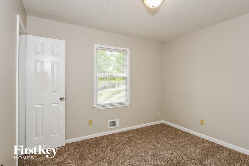 the bedroom of a home with a white door and carpet