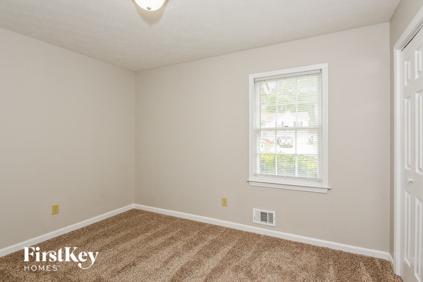 the bedroom of a home with a carpeted floor and a window