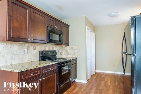 a kitchen with wooden cabinets and black appliances and a refrigerator