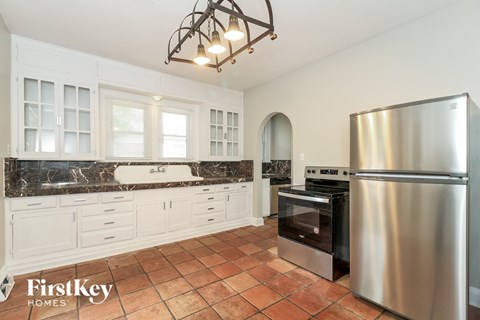 A kitchen with a stainless steel refrigerator and a tile floor.