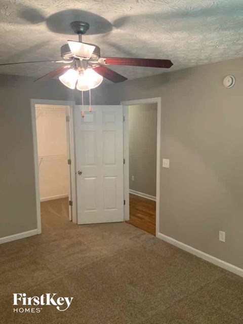 a bedroom with a ceiling fan and a door to a closet