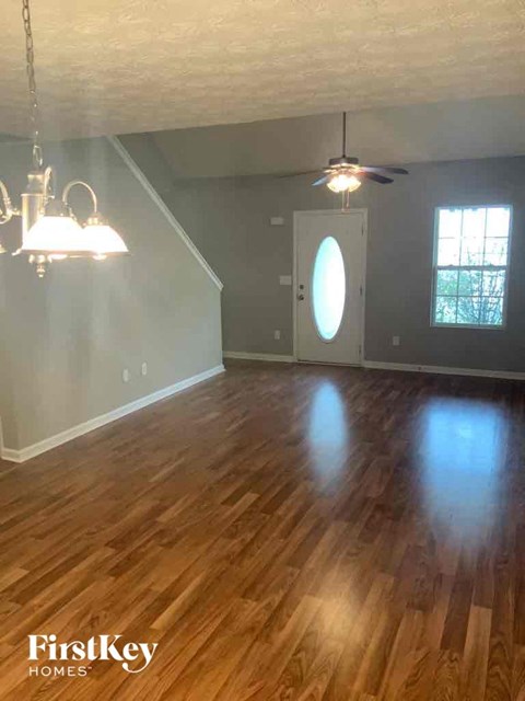 an empty living room with a hard wood floor and a ceiling fan
