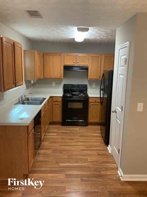 an empty kitchen with wooden cabinets and a black stove