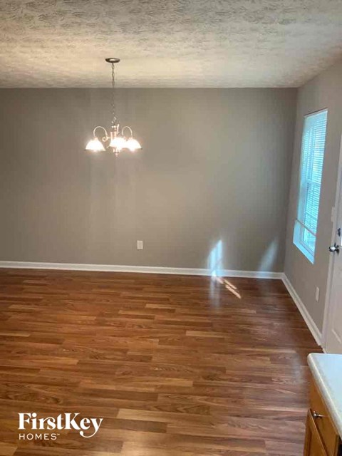 an empty dining room with wooden floors and a chandelier