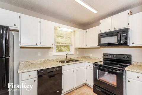 a kitchen with white cabinets and black appliances