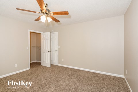 a bedroom with a ceiling fan and a closet