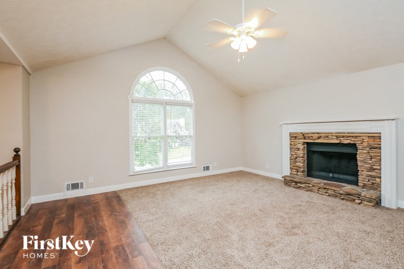an empty living room with a fireplace and a ceiling fan
