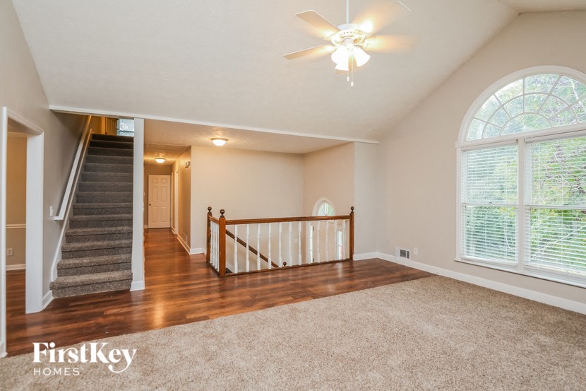 an empty living room with a staircase and a large window