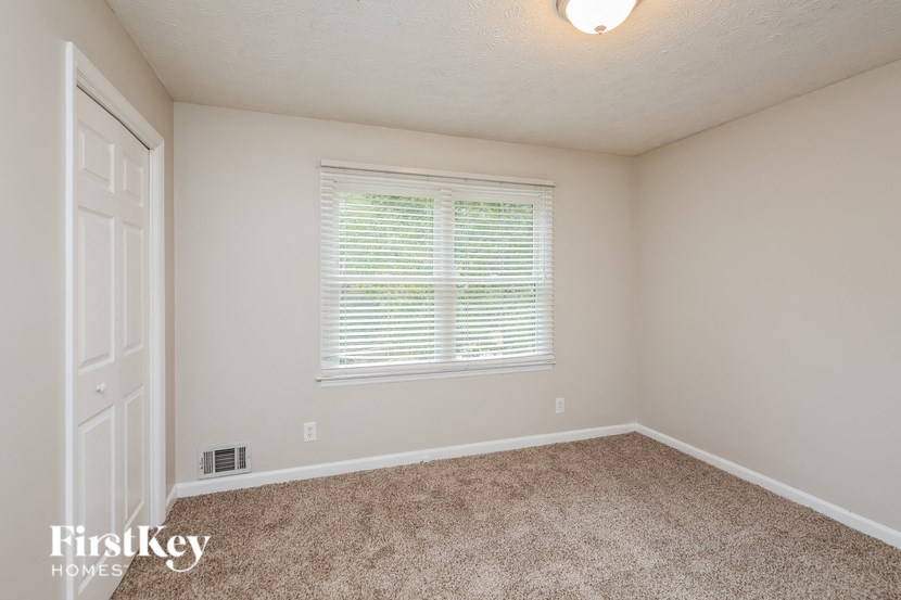a bedroom with a large window and a carpeted floor
