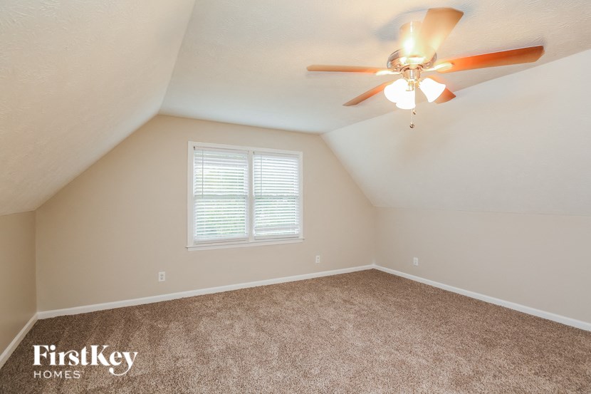an empty bedroom with a ceiling fan and a window