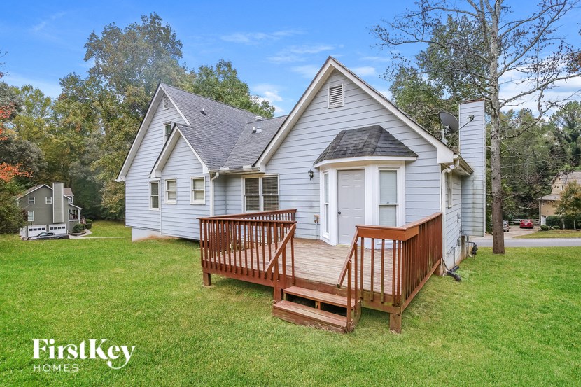 a small white house with a porch and a wooden deck