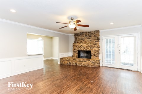 a living room with a stone fireplace and a ceiling fan