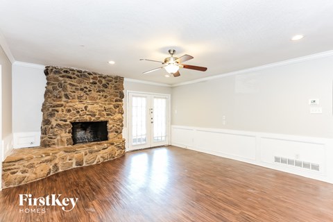 a living room with a stone fireplace and a ceiling fan