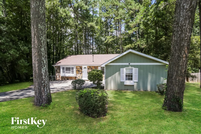 a small green house with a yard and trees