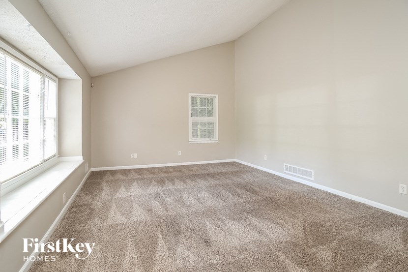 the living room of a home with carpet and a large window