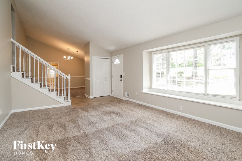 an empty living room with a staircase and a large window