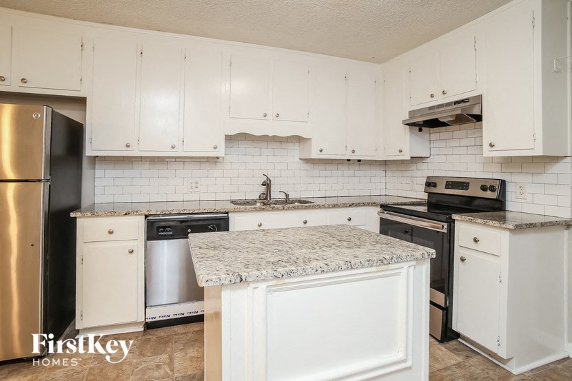 a white kitchen with white cabinets and stainless steel appliances
