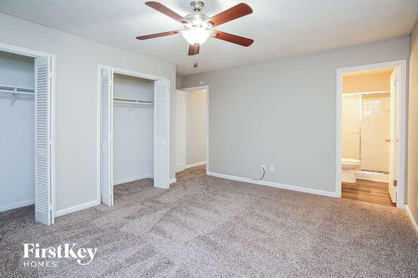 an empty living room with a ceiling fan and a closet