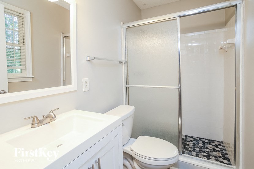 a white bathroom with a shower toilet and sink