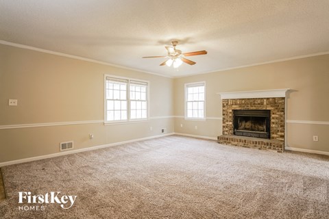the living room of a home with a ceiling fan and a fireplace