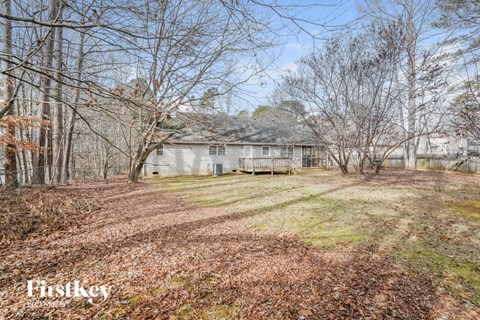 a white house on the side of a yard with trees