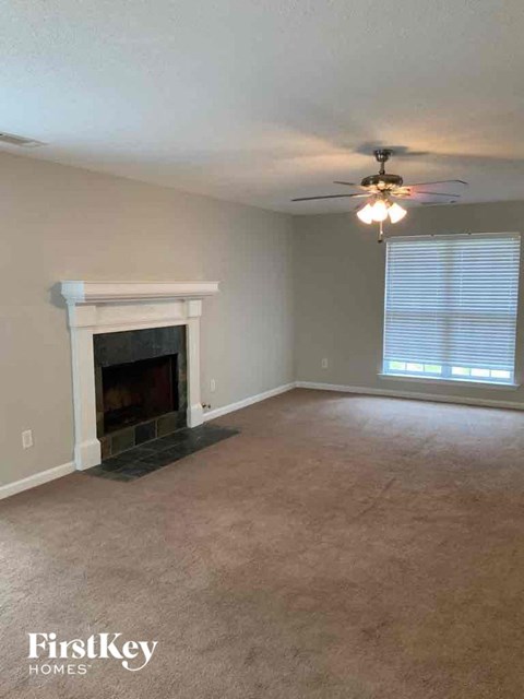 A living room with a fireplace and a ceiling fan.