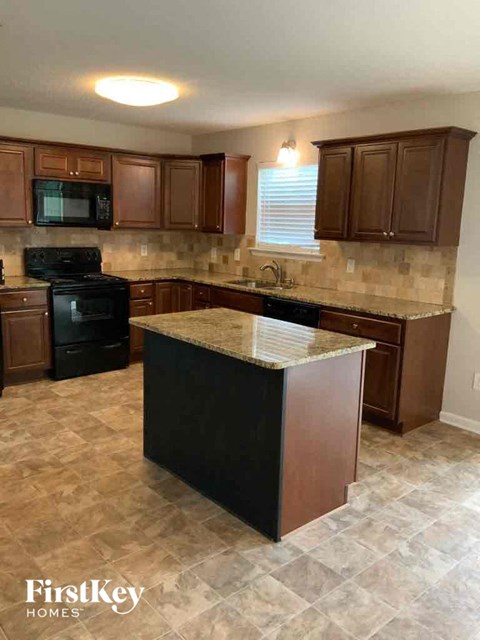 A kitchen with brown cabinets and a black stove top oven.