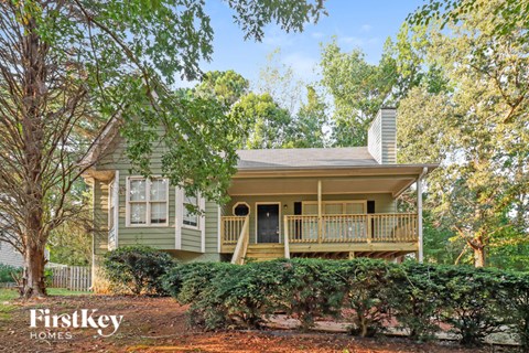 A house with a porch and a tree in front of it.