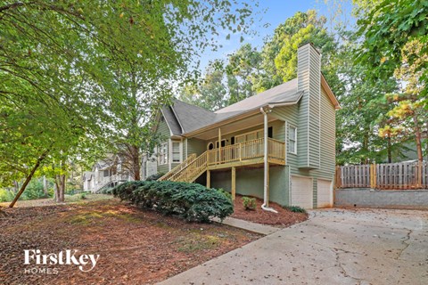 A house with a green front yard and a tree with red leaves.