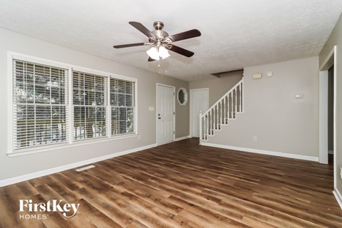 A spacious room with wooden floors and a staircase.