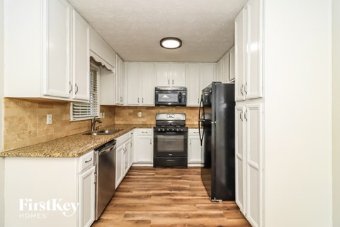 A kitchen with white cabinets and a black refrigerator.