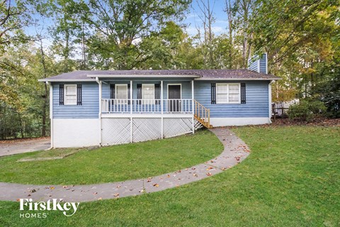 a small blue and white house with a yard and a sidewalk