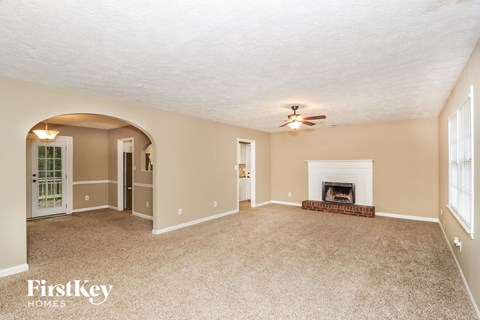 an empty living room with a fireplace and a ceiling fan