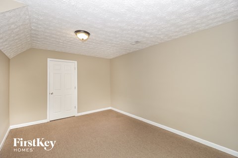 a bedroom with a white door and beige walls and a carpet