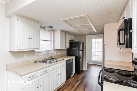 A kitchen with white cabinets and a black refrigerator.