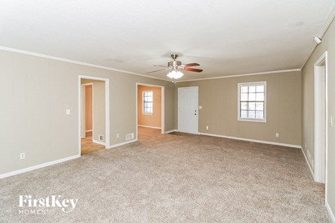a living room with carpet and a ceiling fan