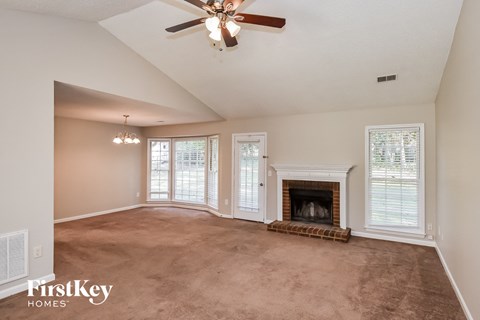 A spacious living room with a fireplace and a ceiling fan.