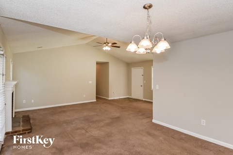 A spacious room with a chandelier and a fireplace on the left side.