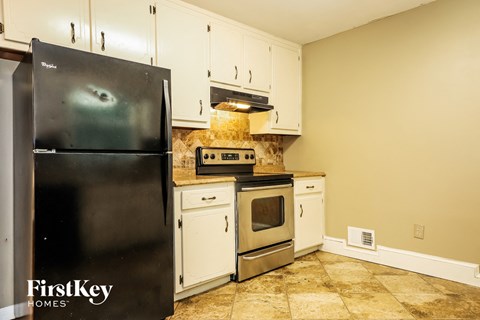 A kitchen with a black fridge and white cabinets.